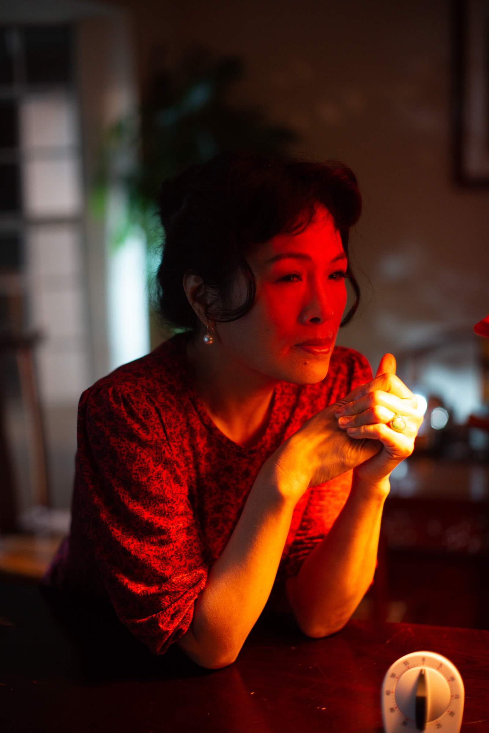 Theatrical portrait of Grace Chang in character, lit in deep red